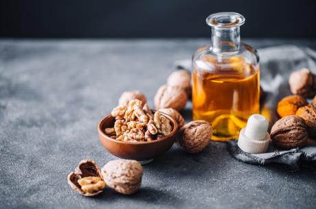 walnuts spread around a small glass bottle of oil.