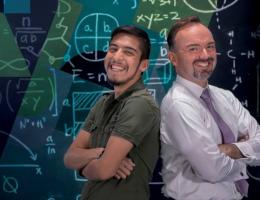 Dr. Aaen and Juan Garcia standing with hands folded in front of a math board